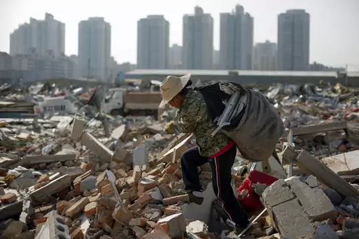 Migrant worker Wang Jun carries scrap material she collected from debris of demolished buildings at the outskirts of Beijing, China October 1, 2017. 