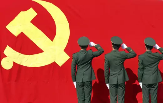 Paramilitary policemen hold their fists in front of a flag of Communist Party of China as they attend an oath-taking rally to ensure the safety of the upcoming 18th National Congress of the Communist Party of China (CPC), at a military base in Hangzhou, Zhejiang province November 5, 2012. 