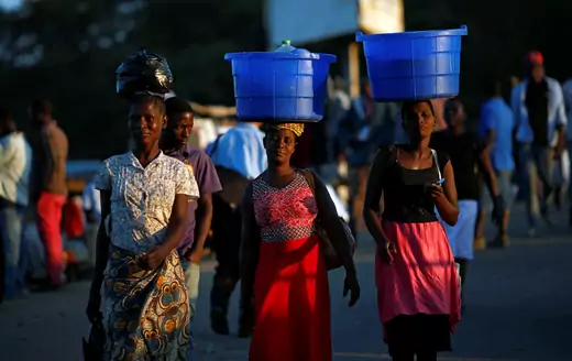 Women carry baskets with food items at a market in Blantyre, Malawi