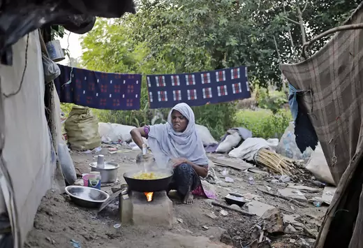 A woman from the Rohingya community from Myanmar cooks food outside her makeshift shelter in a camp in New Delhi, September 13, 2014.