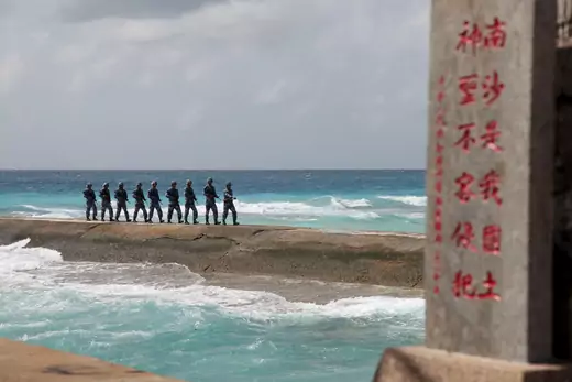 Soldiers of China's People's Liberation Army Navy patrol near a sign in the Spratly Islands.