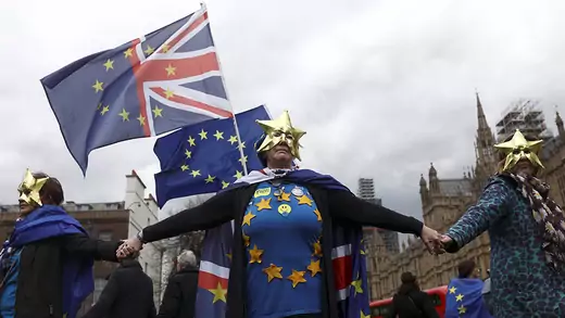 Anti-Brexit protesters wear masks and wave flags during a demonstration in front of the Houses of Parliament in London