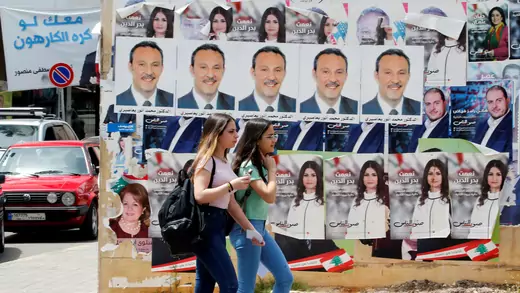 Girls walk past pictures of Lebanese parliament candidates in Beirut.