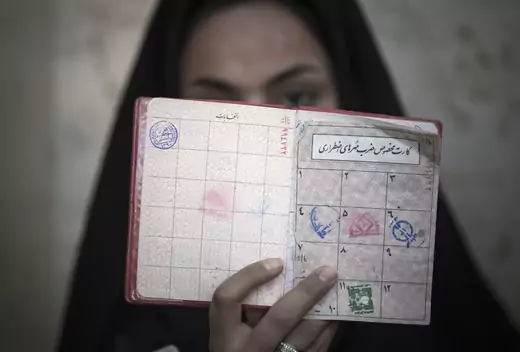 A woman in Iran holds her identification in front of her face after voting March 2, 2012. 