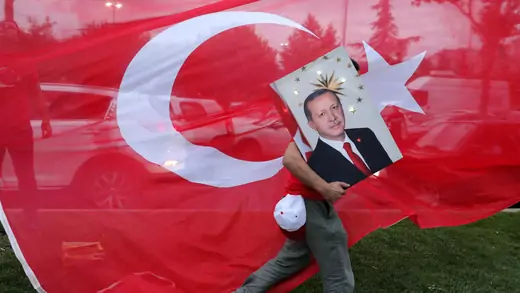 A supporters of Turkish President Tayyip Erdogan holds his picture in front of a Turkish flag, in front of Turkey's ruling AK Party (AKP) headquarters in Istanbul, Turkey. June 24, 2018.
