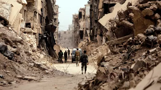 Soldiers walk past damaged buildings in Damascus