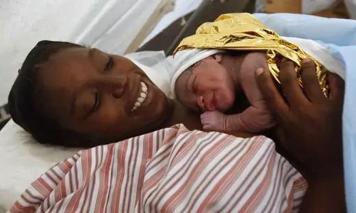 Madame Marcus holds her five-minute-old baby boy after giving birth to her second child at a makeshift hospital run by B-FAST (Belgian First Aid and Support Team).