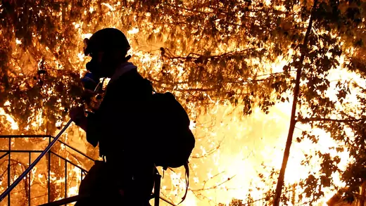 A volunteer sprays water as a wildfire burns near Athens, Greece.