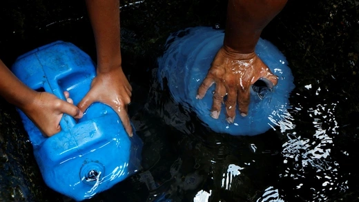 People fill plastic containers with water in a well on the street, close to a neighbourhood called "The Tank" at the slum of Petare in Caracas, Venezuela, April 3, 2016.