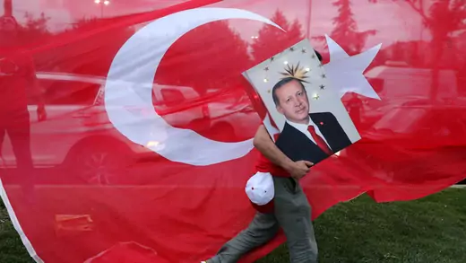 A supporters of Turkish President Tayyip Erdogan holds his picture in front of a Turkish flag, in front of Turkey's ruling AK Party (AKP) headquarters in Istanbul,Turkey, June 24, 2018.