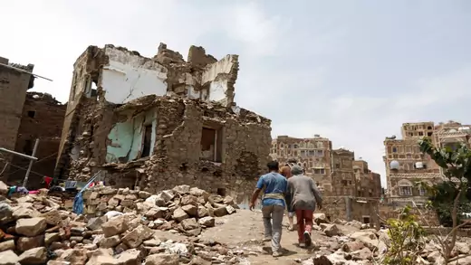 People walk past a house destroyed by an airstrike in Sanaa, Yemen.