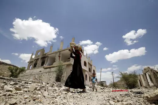 A woman and a boy walk past the ruins of buildings destroyed in Saudi-led air strikes in Yemen's capital Sanaa. September 13, 2015.