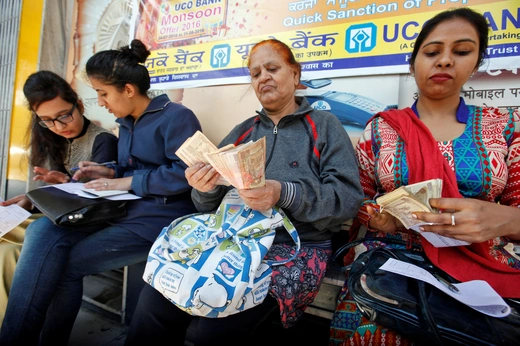 Women count Indian rupee banknotes before depositing them at a bank in Chandigarh, India. November 10, 2016.