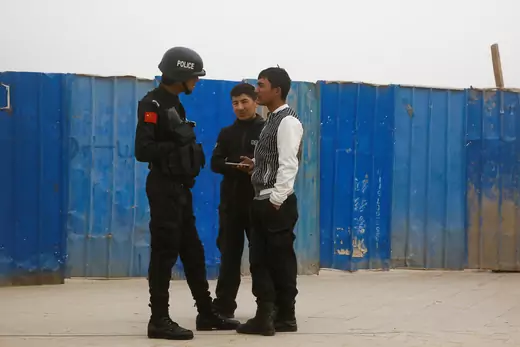 A police officer talks to men in a street in Kashgar, Xinjiang Uighur Autonomous Region, China, March 24, 2017. 