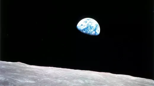 Earth rises beyond the lunar horizon.