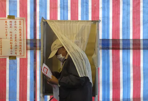 A man wearing a health mask walks out of a voting booth in Xinbei, Taiwan. 
