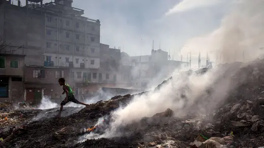 A child runs beside the waste-burning area of a dump in Dhaka, Bangladesh. 