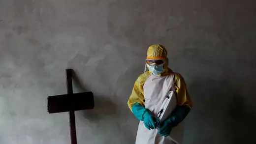 A health-care worker stands next to a cross during the funeral of a person suspected of dying of Ebola in Beni, Democratic Republic of Congo.