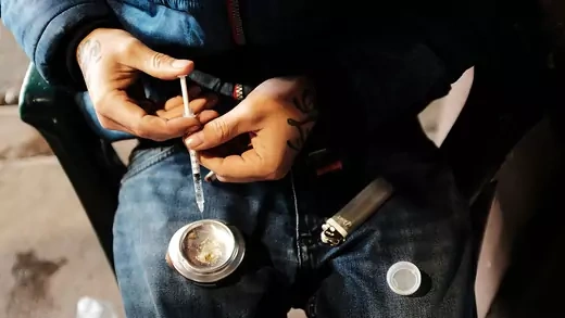 A man uses heroin under a bridge where he lives with other addicts in Philadelphia, Pennsylvania.