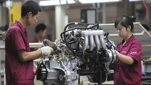 Employees assemble an engine at the production line of an automobile company in Anhui province, China. July 16, 2009.