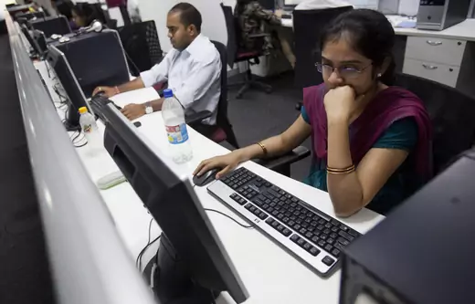 Employees work on their computer terminals on the floor of an outsourcing centre in Bangalore