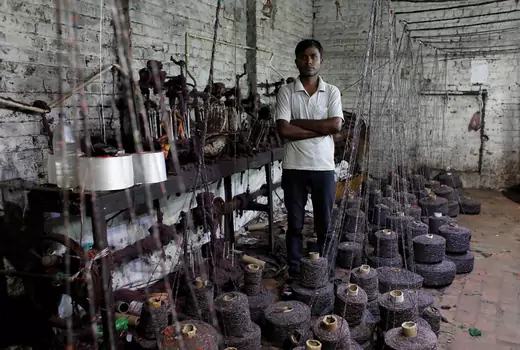 Ram Pratap, who lost his job as a powerloom operator earlier this year, poses for a picture inside a weaving factory where he used to work, in Panipat in the northern state of Haryana, India
