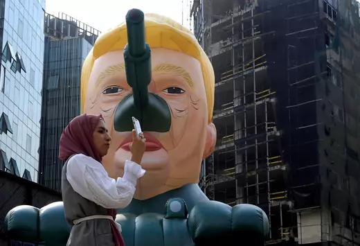 A woman stands next to an inflatable tank with U.S. President Donald Trump outside an art exhibition 'MonuMental' by the pseudonymous artist, Saint Hoax in downtown Beirut, Lebanon October 12, 2018