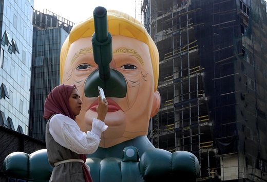 A woman stands next to an inflatable tank with U.S. President Donald Trump outside an art exhibition 'MonuMental' by the pseudonymous artist, Saint Hoax in downtown Beirut, Lebanon October 12, 2018. 