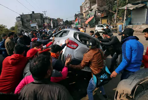 Demonstrators overturn a car during a protest in Jammu
