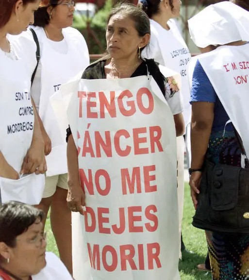 A group of protesters stand outside the World Trade Organization ministerial meeting venue in Cancun, September 10, 2003. The sign reads: "I have cancer, don't let me die."