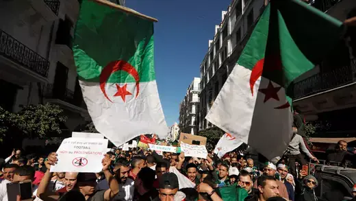 People carry their national flags as they gather during a protest over President Abdelaziz Bouteflika's decision to postpone elections and extend his fourth term in office, in Algiers, Algeria March 15, 2019