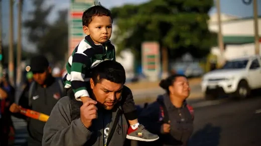 Father and son walk in a caravan of migrants en route to U.S. in San Salvador