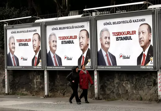 People walk past by AK Party billboards with pictures of Turkish President Tayyip Erdogan and mayoral candidate Binali Yildirim in Istanbul, Turkey, April 1, 2019.