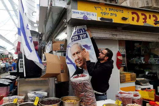 A man holds a Likud election campaign poster depicting Israeli Prime Minister Benjamin Netanyahu in Jerusalem April 8, 2019. 