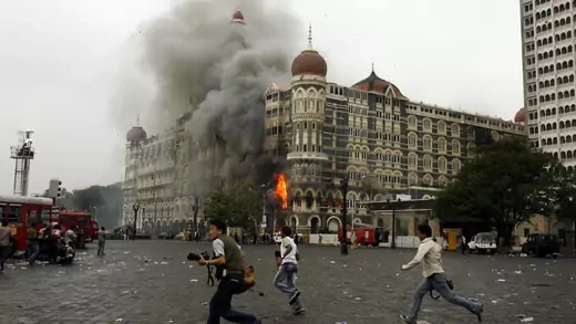 Photographers run past a burning Taj Mahal Hotel.