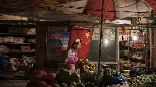 An ethnic Uyghur shopkeeper works next to a Chinese flag at his shop on June 29, 2017 in the old town of Kashgar, in the far western Xinjiang province, China.