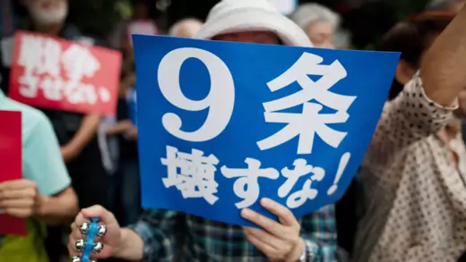 Japanese protester holding sign about article 9