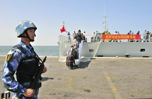 A navy soldier of the People's Liberation Army (PLA) stands guard as Chinese citizens board the naval ship "Linyi" at a port in Aden, Yemen March 29, 2015. 