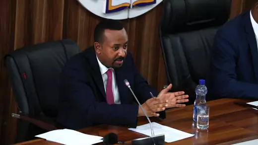 Prime Minister Abiy Ahmed sits at a desk in parliament and responds to questions