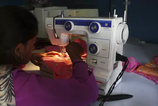 A woman sews clothes on a sewing machine driven by solar energy in India, September 10, 2009.