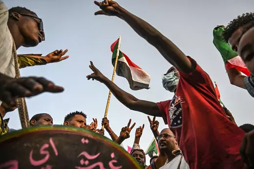 Sudanese protesters wave national flags and shout slogans during a protest outside the army complex in the capital Khartoum