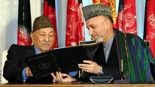 Afghan President Hamid Karzai shows the constitution to former king Zahir Shah.