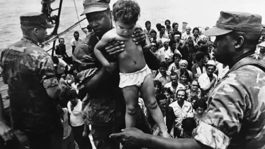 A U.S. Marine helps a  child off of a Cuban refugee boat.