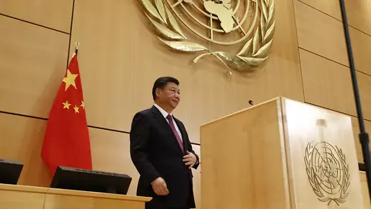 Chinese President Xi Jinping stands behind a wooden podium with the United Nations logo in gold. A Chinese flag is behind him.
