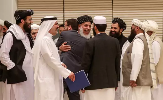 Taliban negotiator Abbas Stanikzai embraces a man during the second day of the Intra Afghan Dialogue talks in Doha.