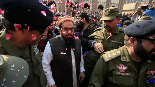 File photo: Supporters shower Hafiz Saeed with flower petals as he walks to court in Lahore, Pakistan, in November 2017. The court released him from house arrest.  