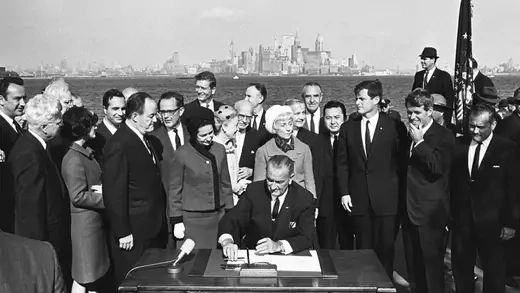 President Lyndon B. Johnson signs the 1965 Immigration Act at the foot of the Statue of Liberty. 
