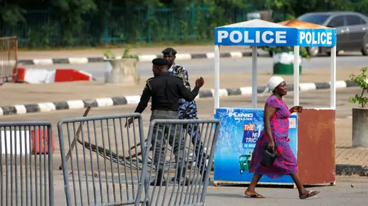 A woman walks by police at a barricade in Abuja, Nigeria. 