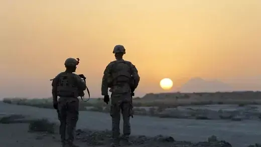 U.S. soldiers stand at sunset at a temporary checkpoint in Dand district.
