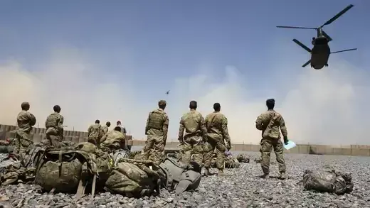 U.S. soldiers looking at helicopters carrying U.S. Army soldiers.